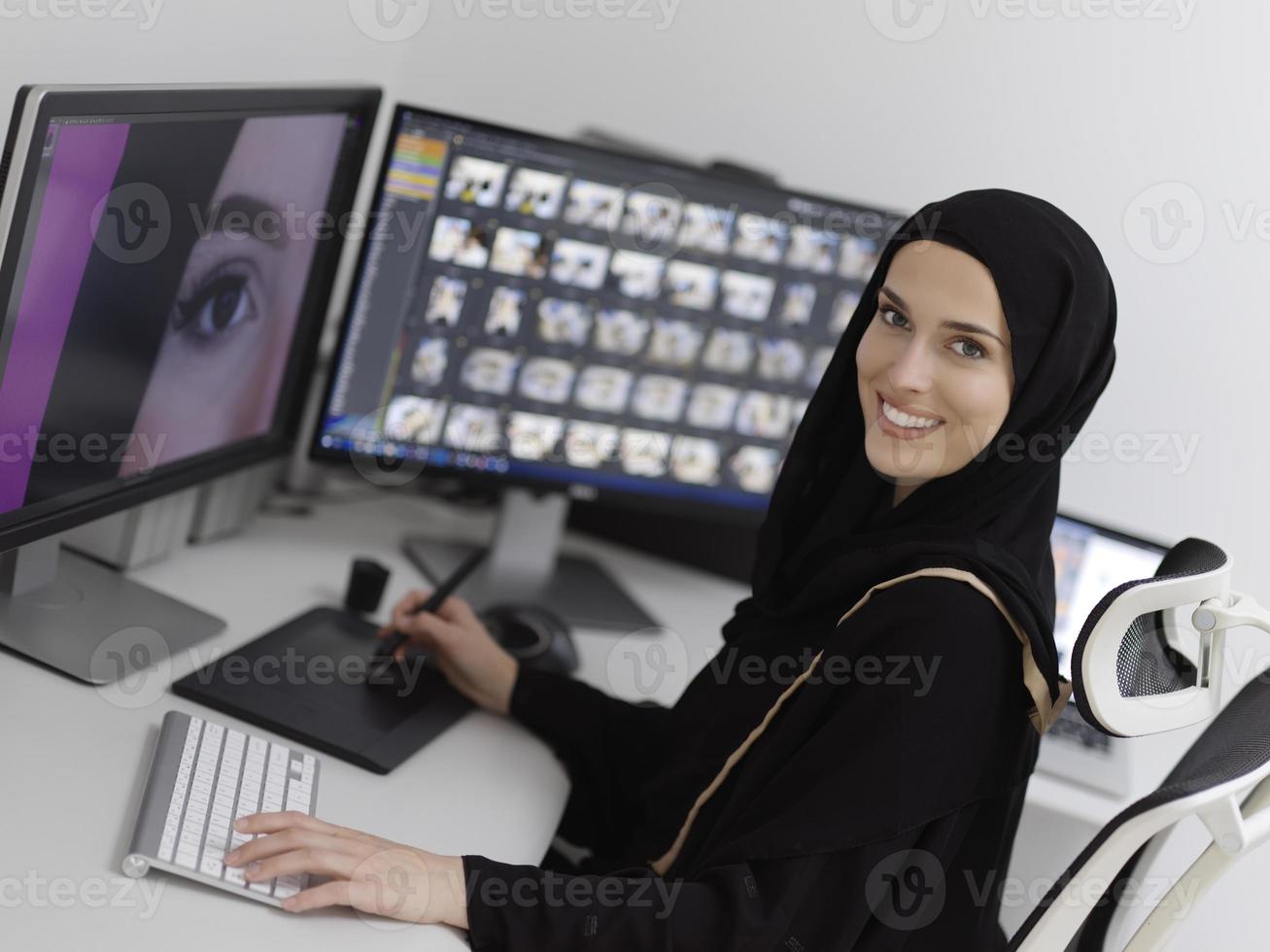 Muslim female graphic designer working on computer using graphic tablet and two monitors photo