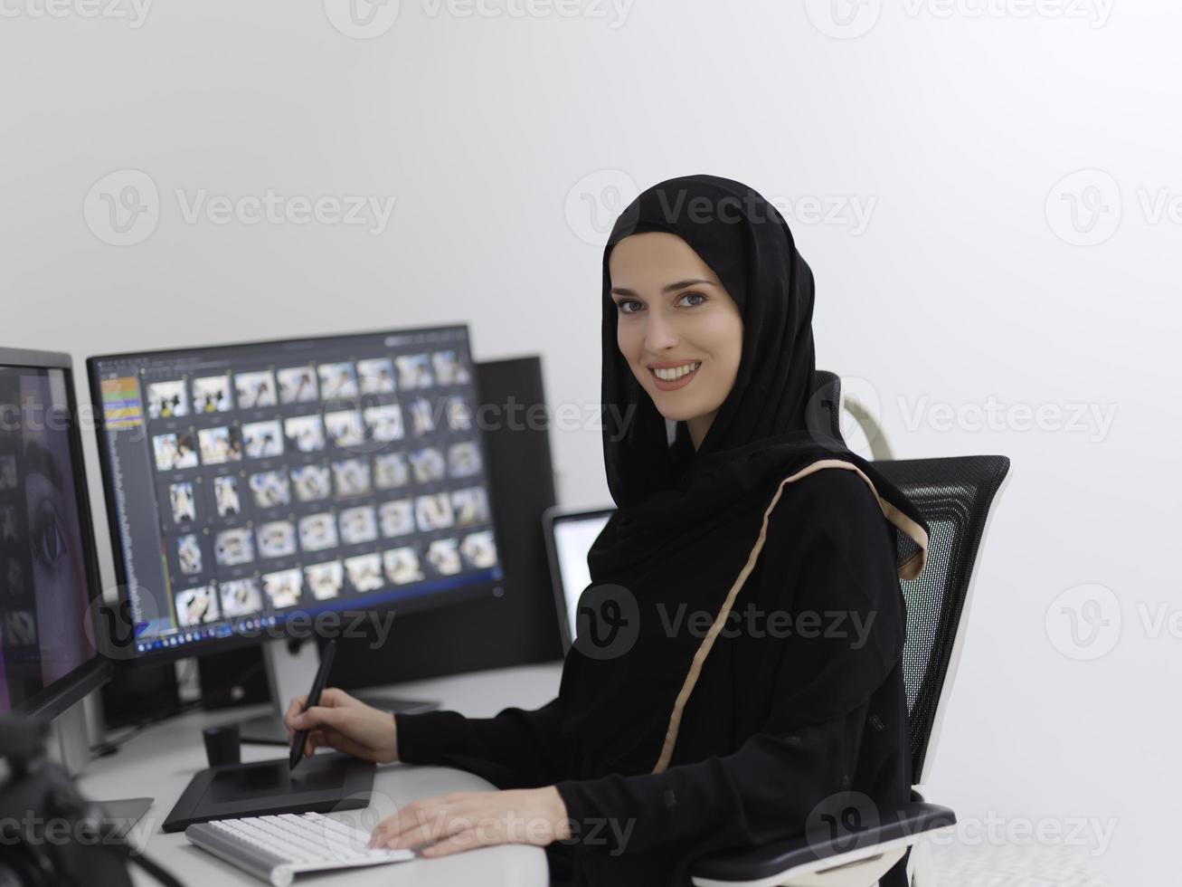 Muslim female graphic designer working on computer using graphic tablet and two monitors photo