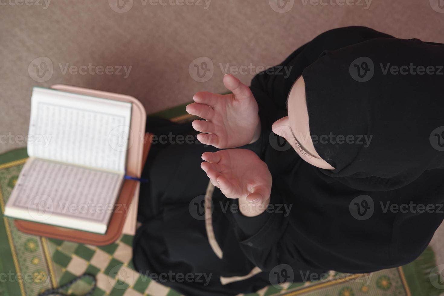 Middle eastern woman praying and reading the holy Quran photo