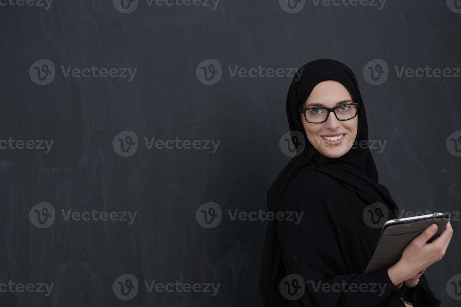 Young Arab businesswoman in traditional clothes or abaya holding tablet computer photo