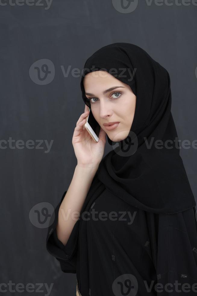 joven mujer de negocios musulmana con ropa tradicional o abaya hablando por teléfono inteligente foto