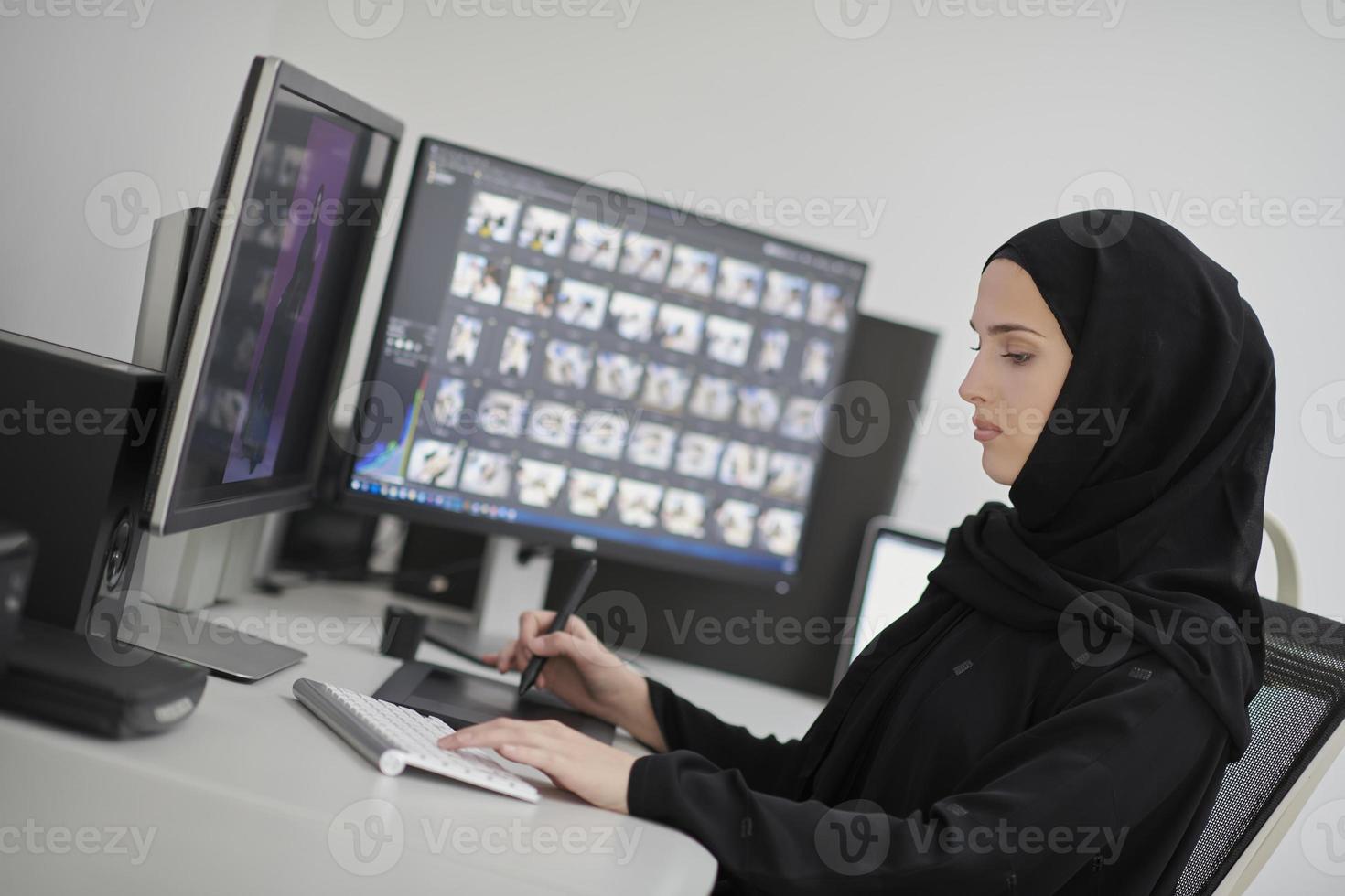 Muslim female graphic designer working on computer using graphic tablet and two monitors photo