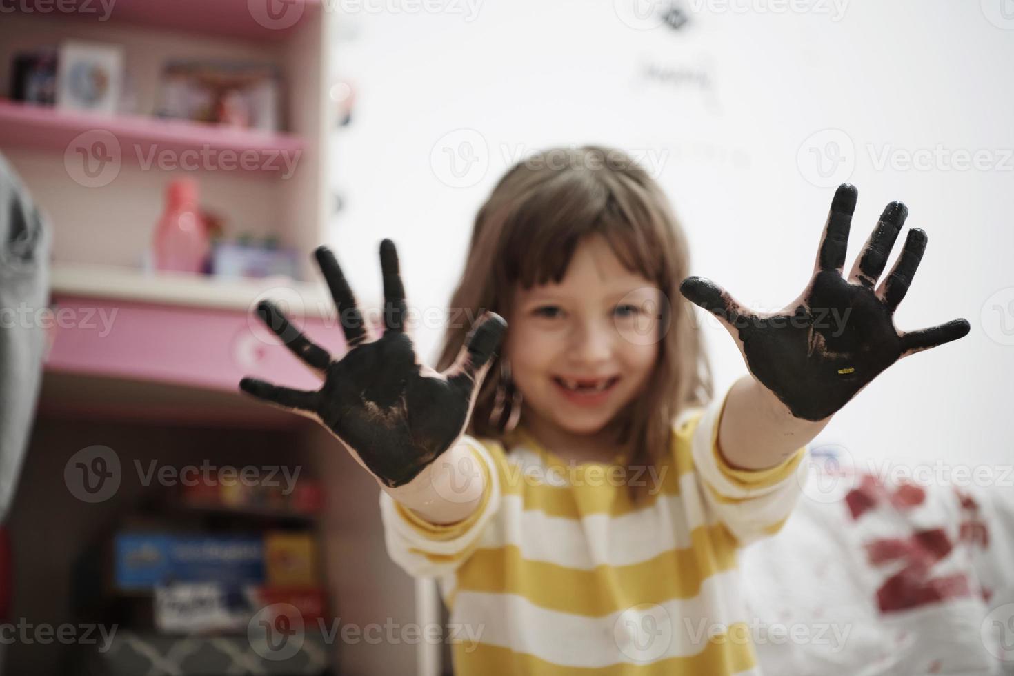 linda niña en casa pintando con las manos foto