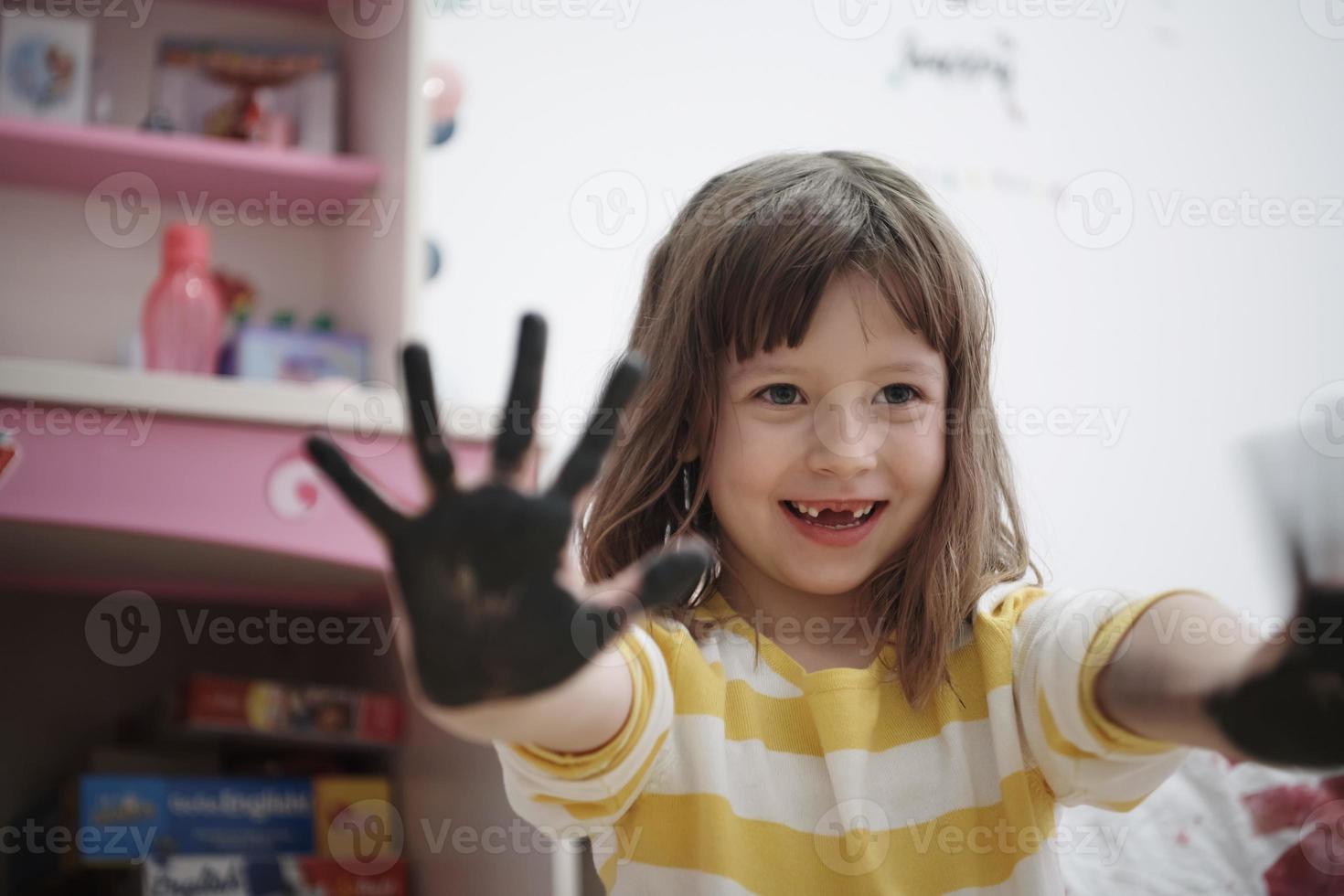 linda niña en casa pintando con las manos foto