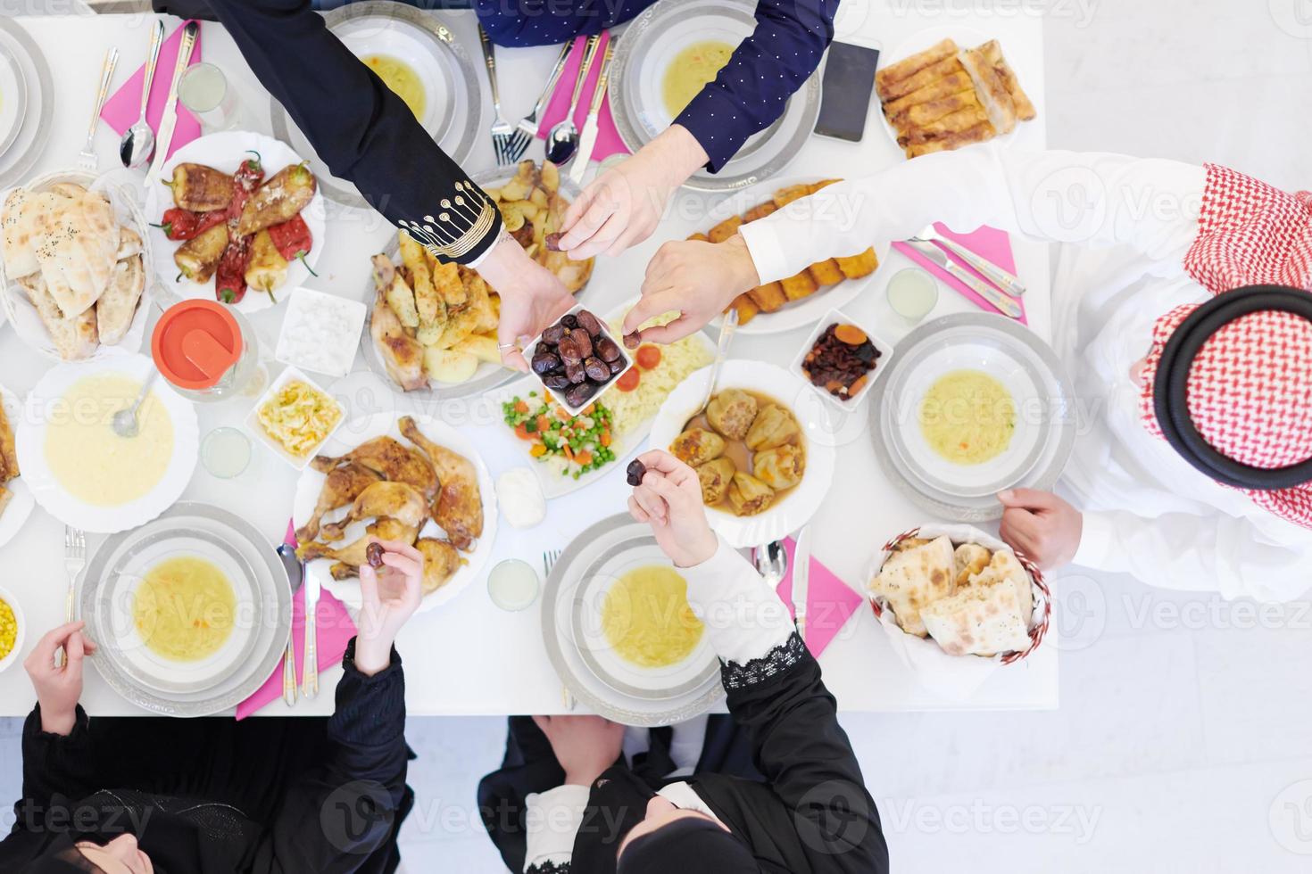 Muslim family having Iftar dinner eating dates to break feast top view photo