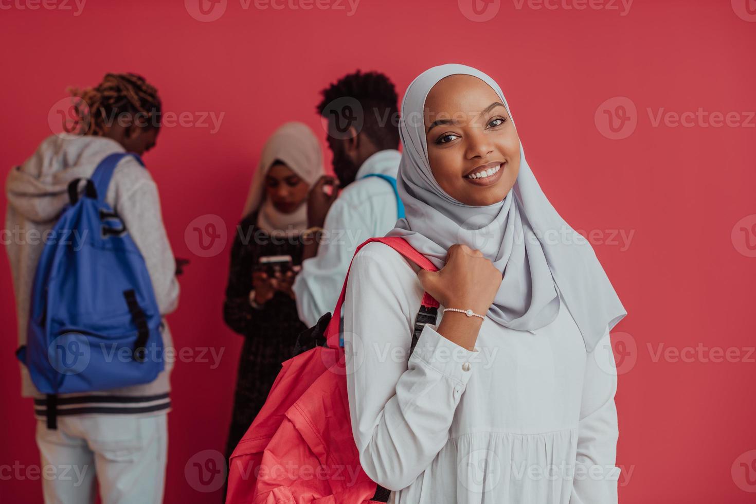 A group of African Muslim students with backpacks posing on a pink background. the concept of school education. photo