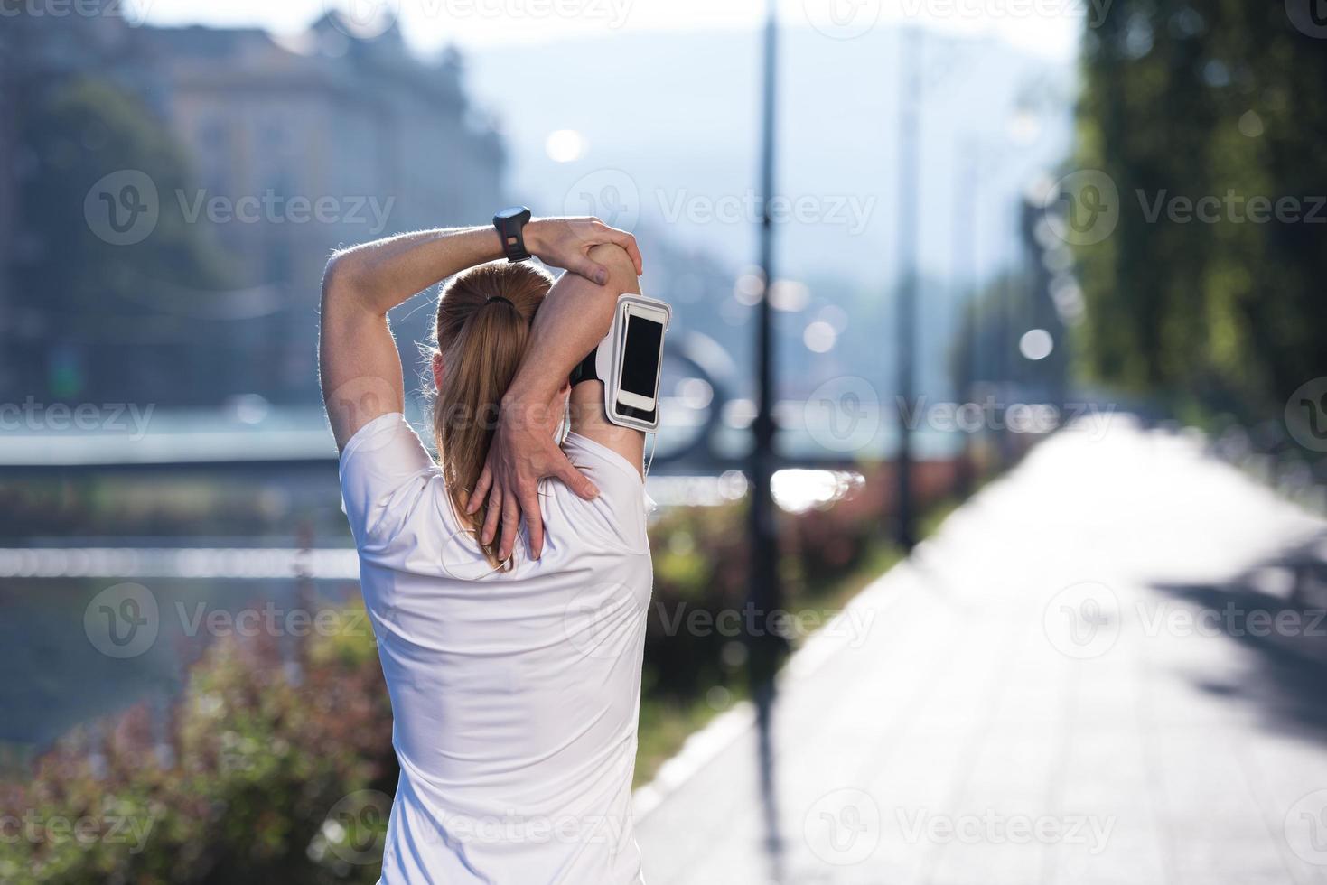 mujer rubia que se extiende antes de trotar por la mañana foto