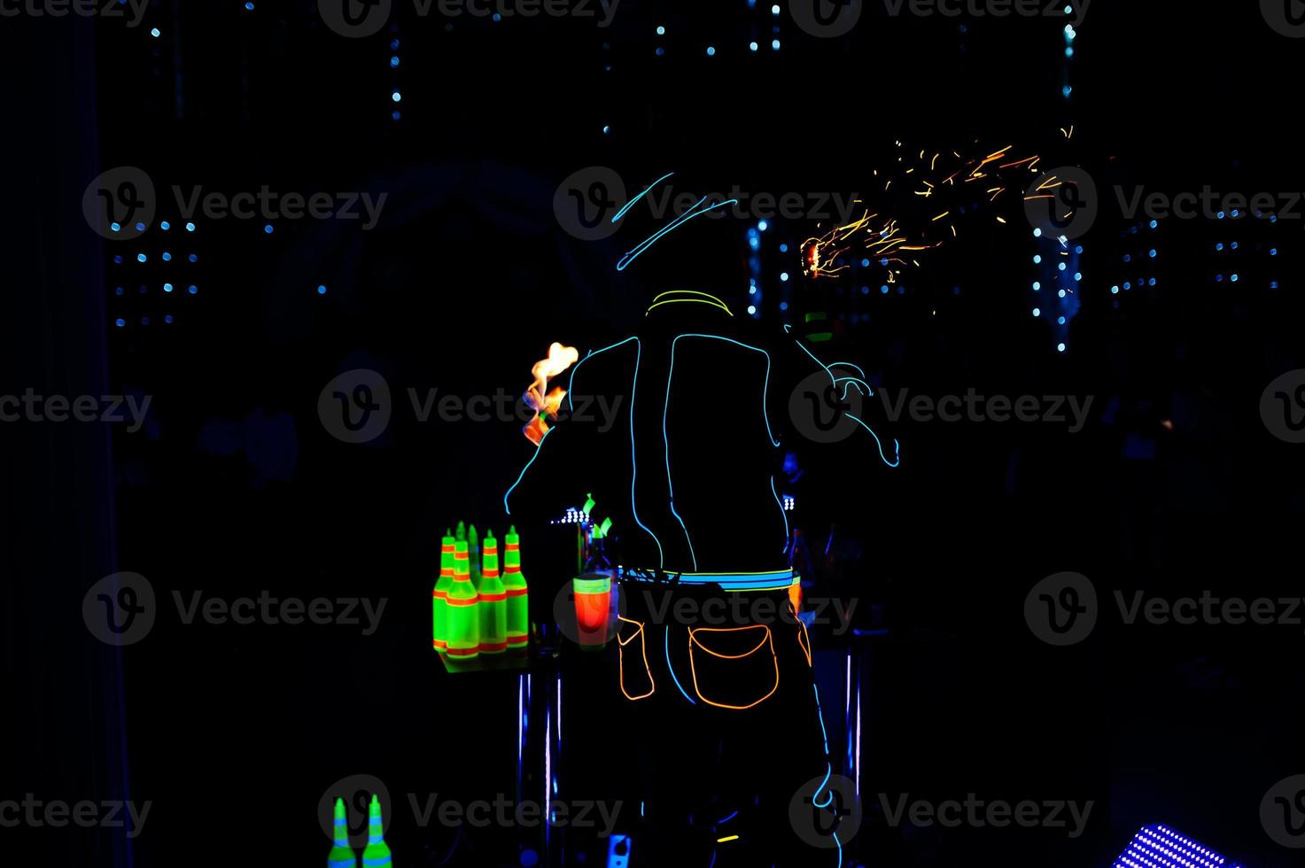 Professional barman and led light fire show. Silhouette of modern bartender shaking drink at night cocktail bar. photo