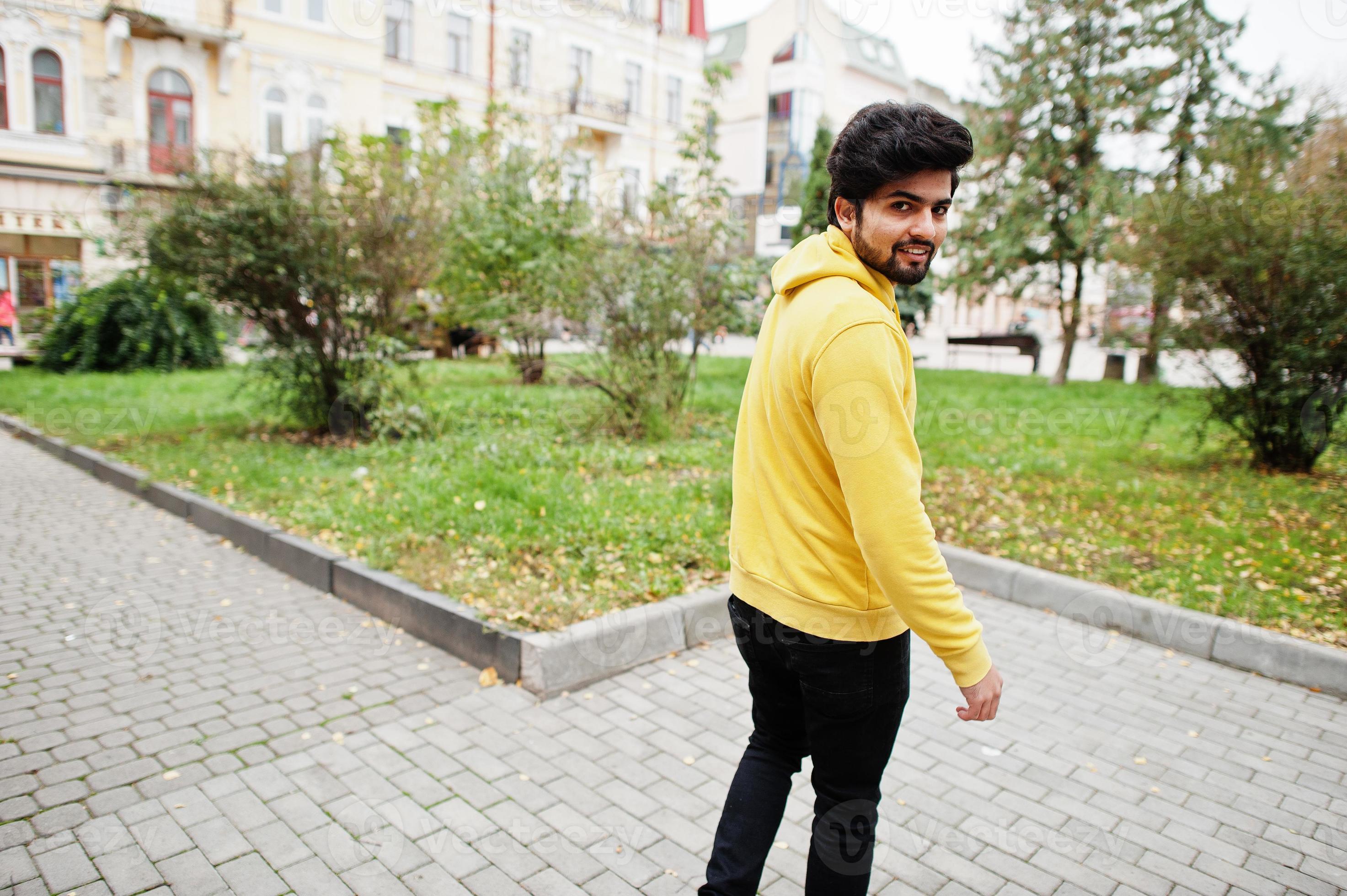 hombre indio joven hipster urbano en una sudadera amarilla de moda