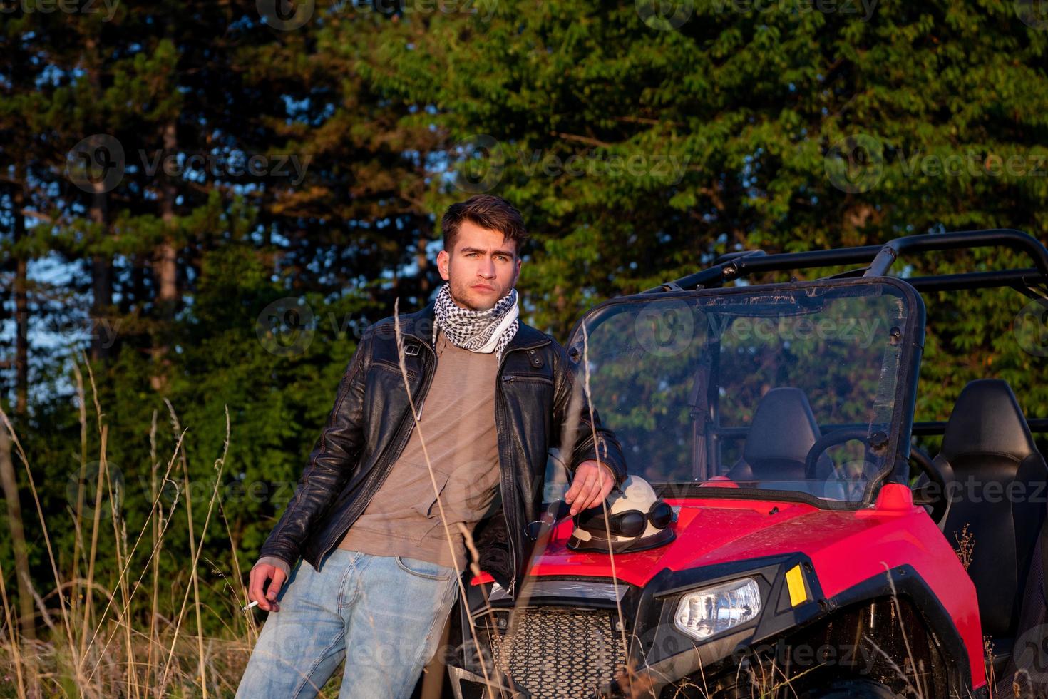 young man taking a break from driving a off road buggy car photo