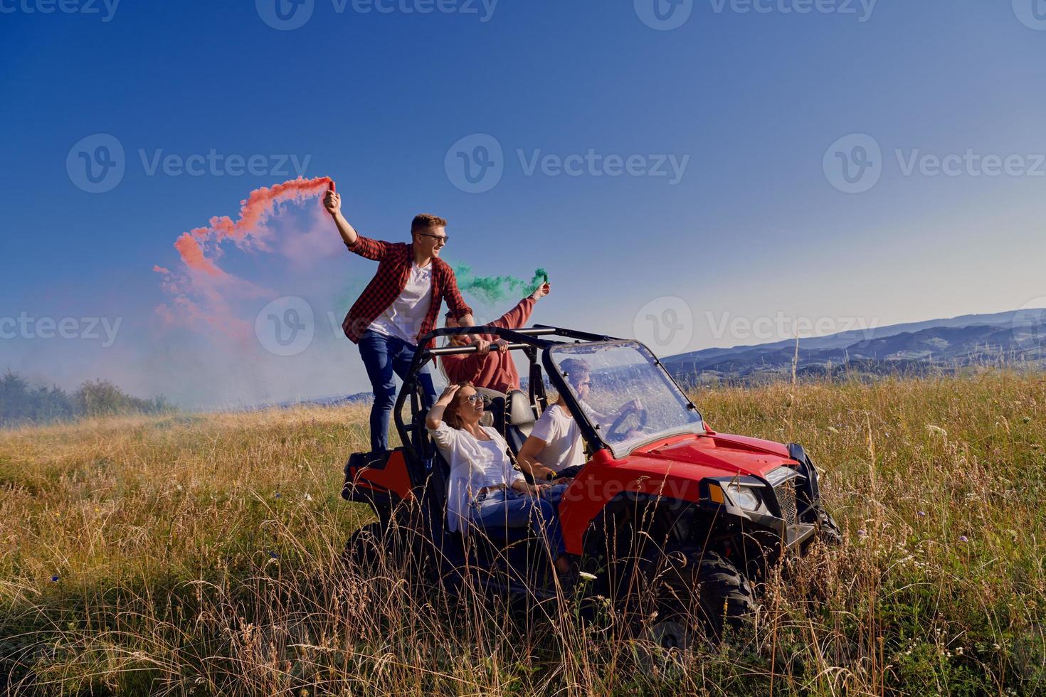 excited people having fun enjoying beautiful sunny day holding colorful torches while driving a off road buggy car photo