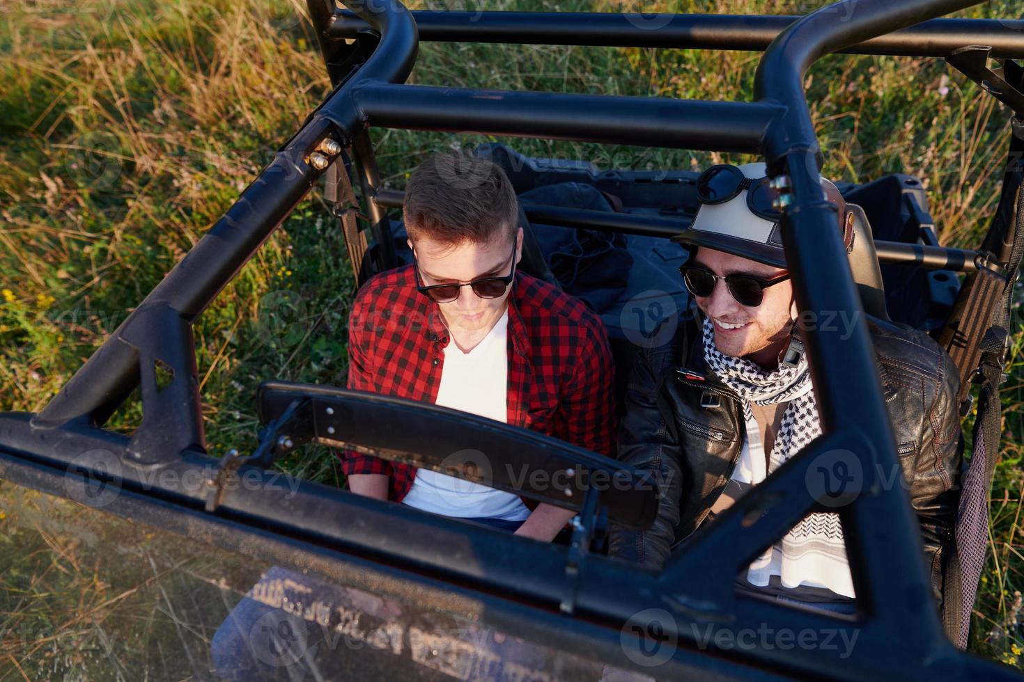 two young happy excited men enjoying beautiful sunny day while driving a off road buggy car photo