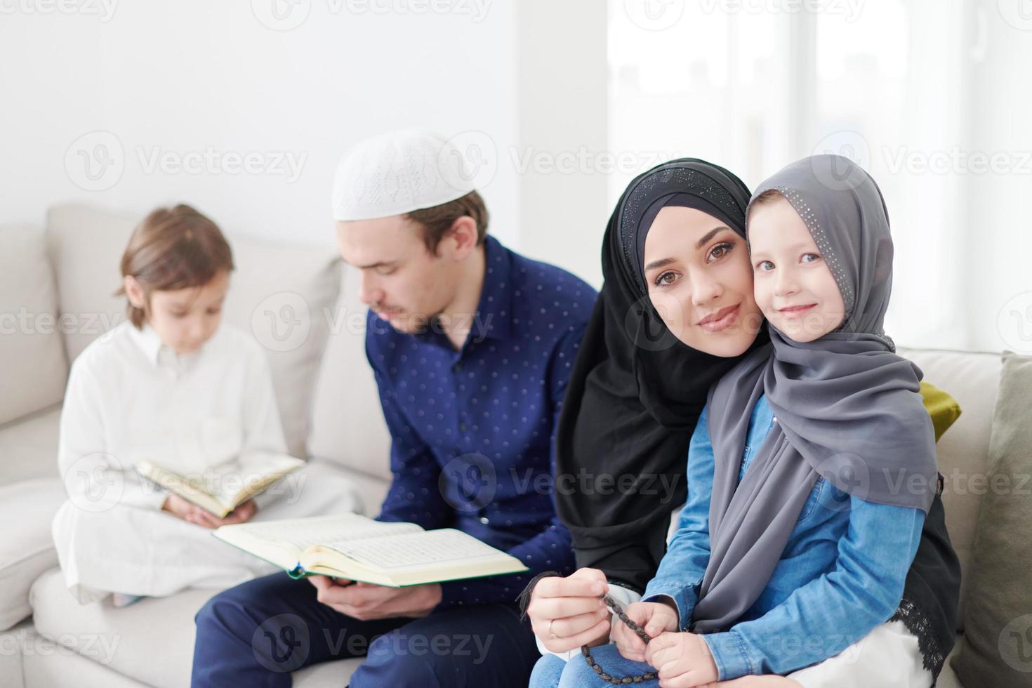 familia musulmana leyendo el corán y rezando en casa foto