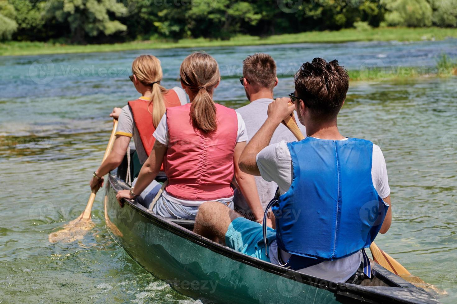 Group adventurous explorer friends are canoeing in a wild river photo