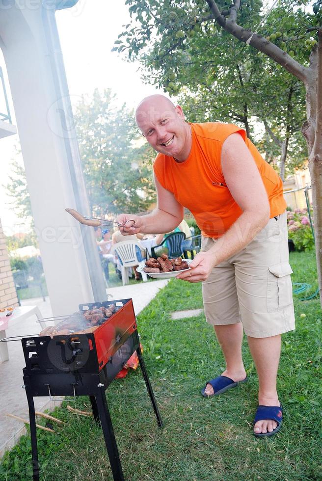 happy man preparing sausages on grill photo