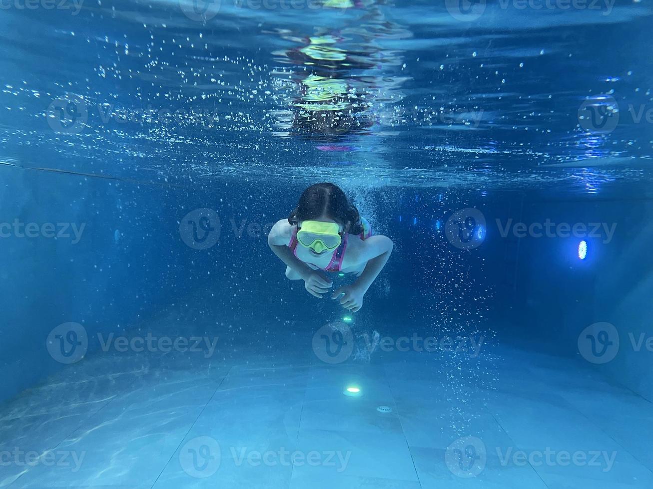 Smiling child in goggles swim, dive in the pool with fun - jump deep down underwater. Healthy lifestyle, people water sport activity on summers. photo