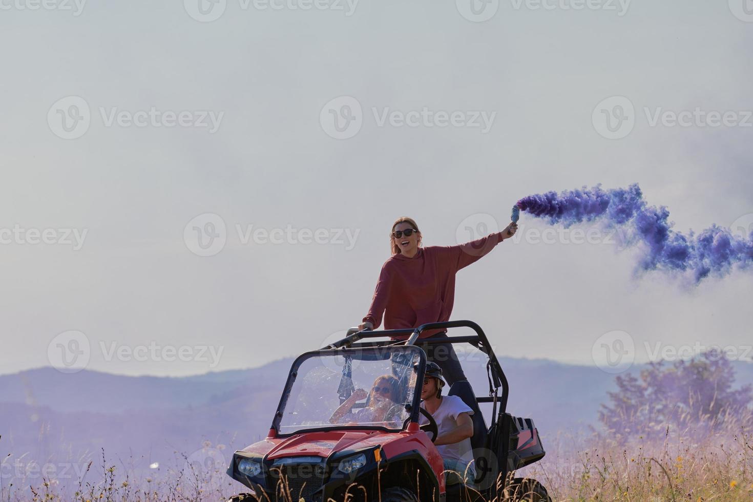 excited people having fun enjoying beautiful sunny day holding colorful torches while driving a off road buggy car photo