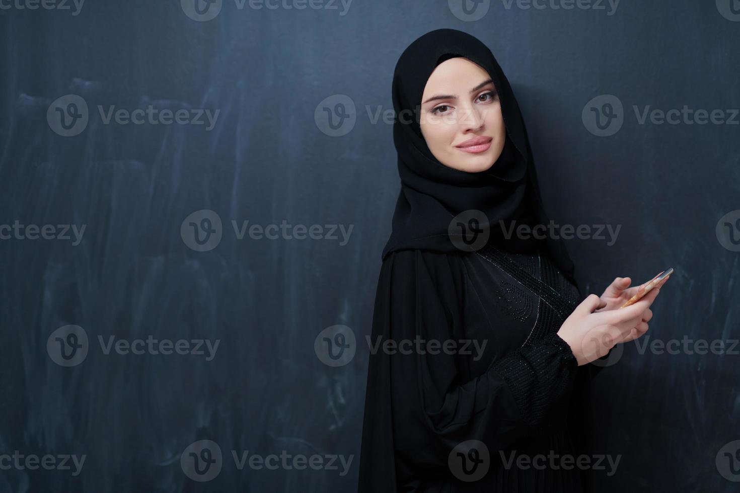 Young muslim businesswoman in traditional clothes or abaya using smartphone photo