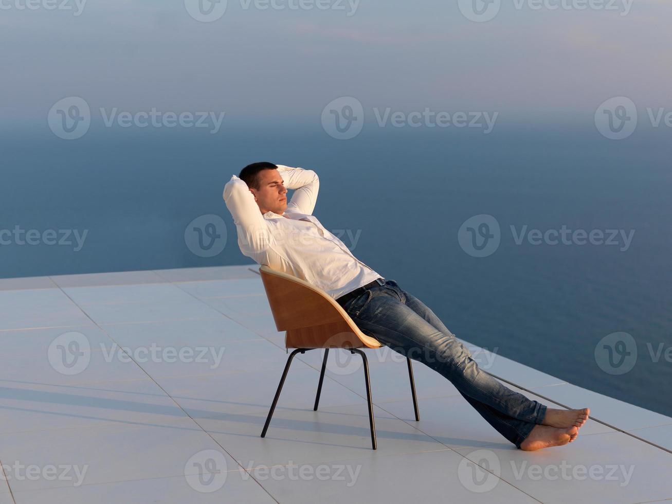 relaxed young man at home on balcony photo