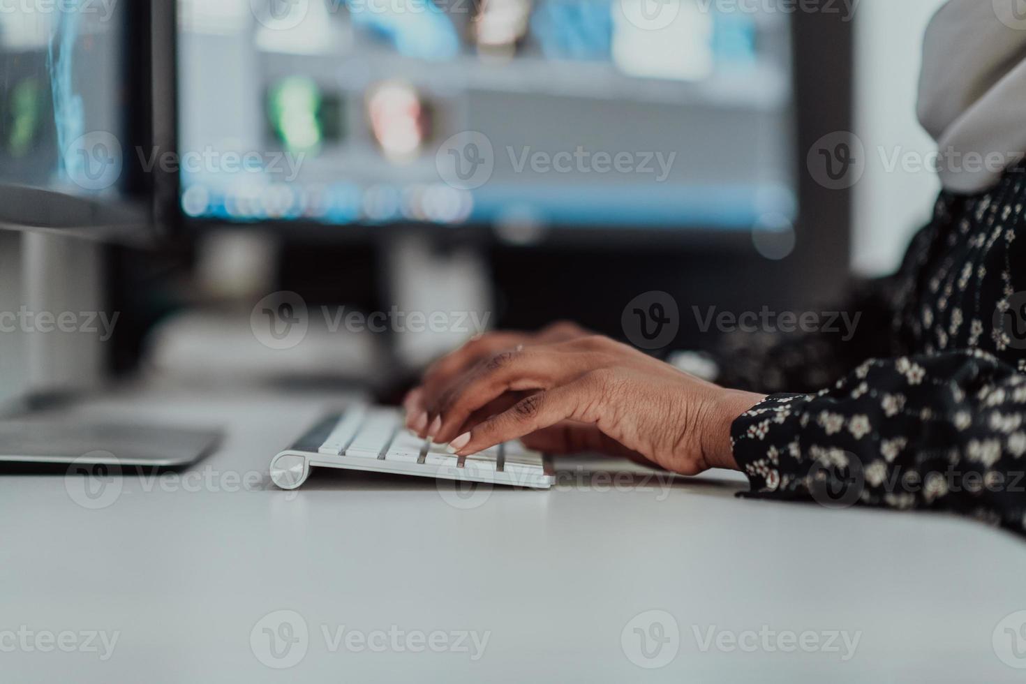 joven mujer de negocios musulmana moderna afroamericana que usa una bufanda en un lugar de trabajo creativo y brillante con una pantalla grande. foto