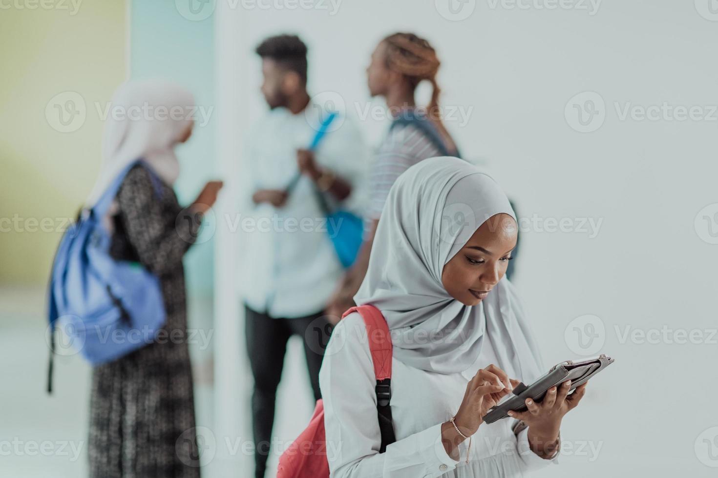 African female student with group of friends in background wearing traditional Islamic hijab clothes. Selectve focus photo