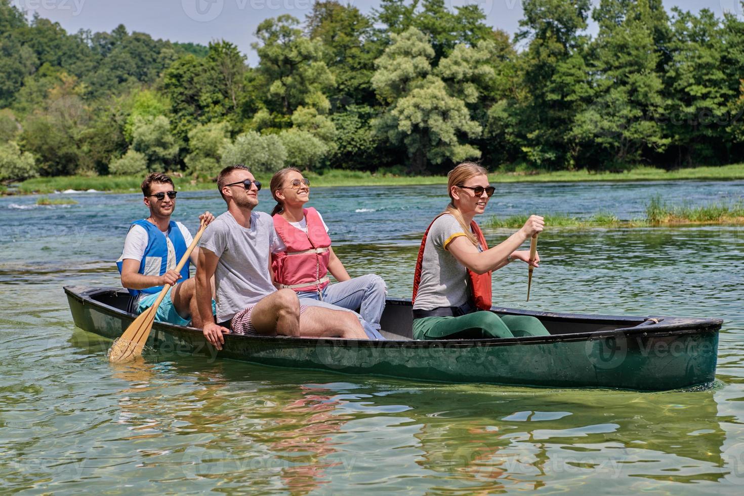 Group adventurous explorer friends are canoeing in a wild river photo