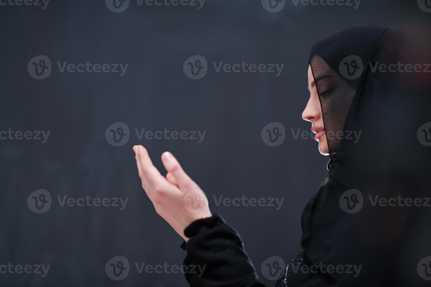 muslim woman making traditional prayer to God in front of black chalkboard photo