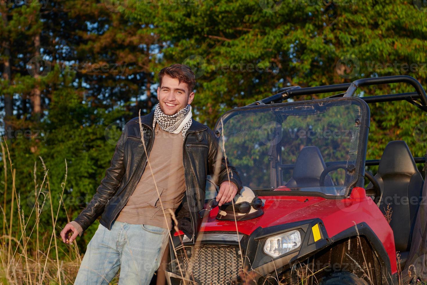 man enjoying beautiful sunny day smoking a cigarette while taking a break from driving a off road buggy car photo