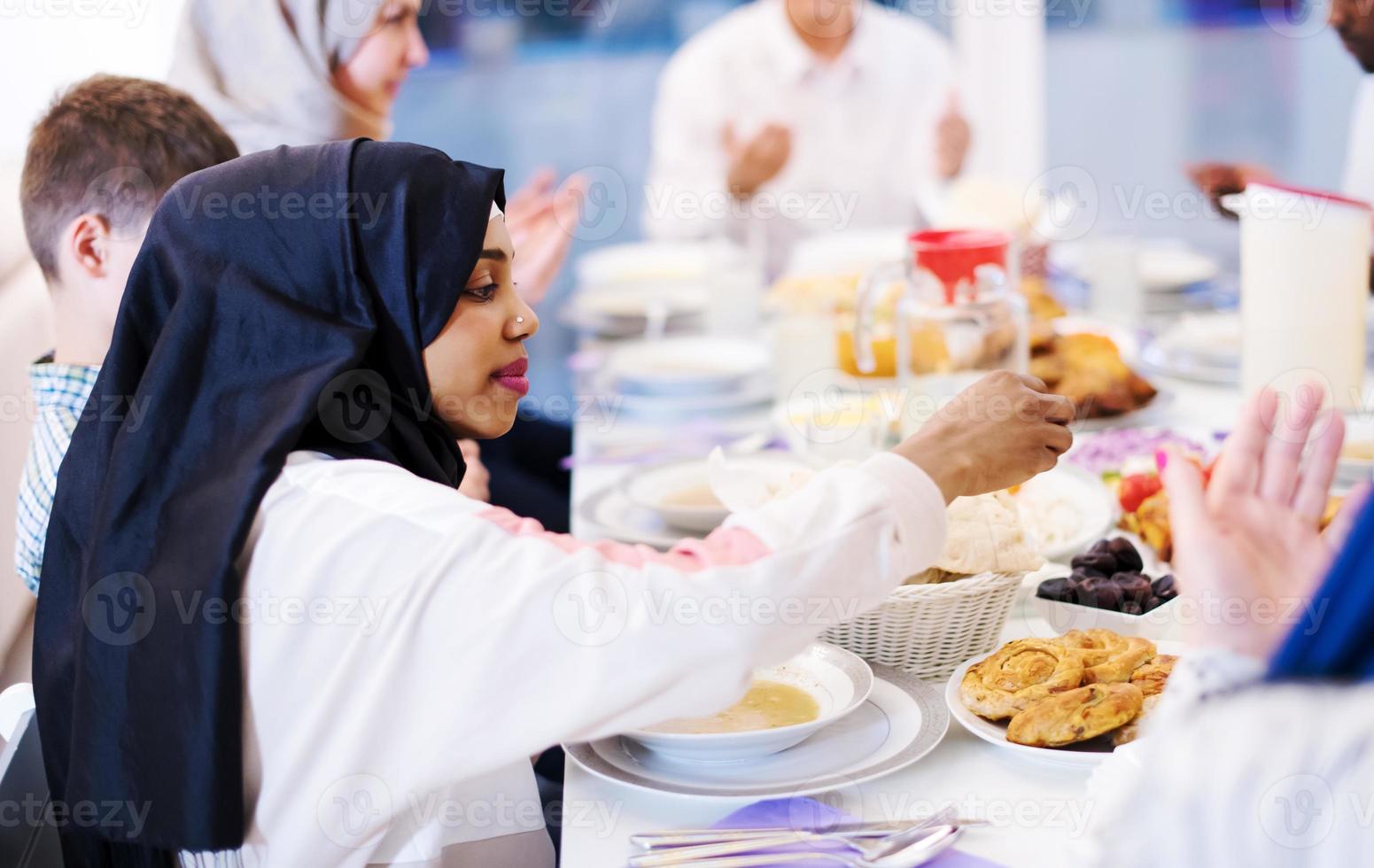 mujer musulmana moderna negra disfrutando de la cena iftar con la familia foto