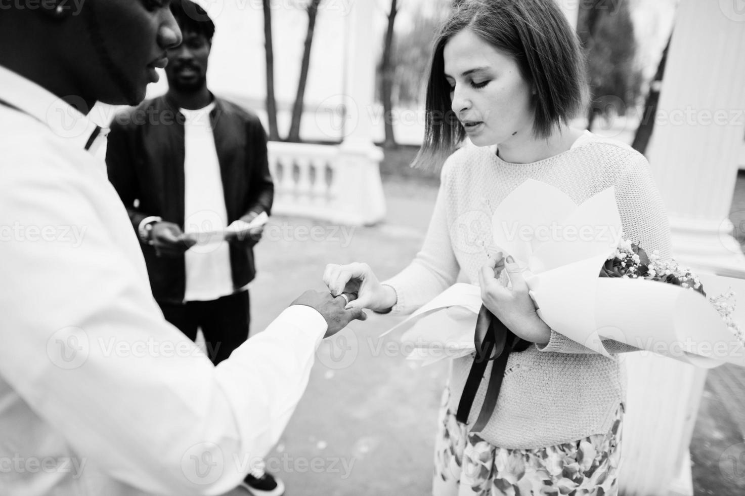 ceremonia de compromiso de boda con el pastor. pareja multiétnica se pone anillo. relaciones de hombre africano y mujer europea blanca. foto