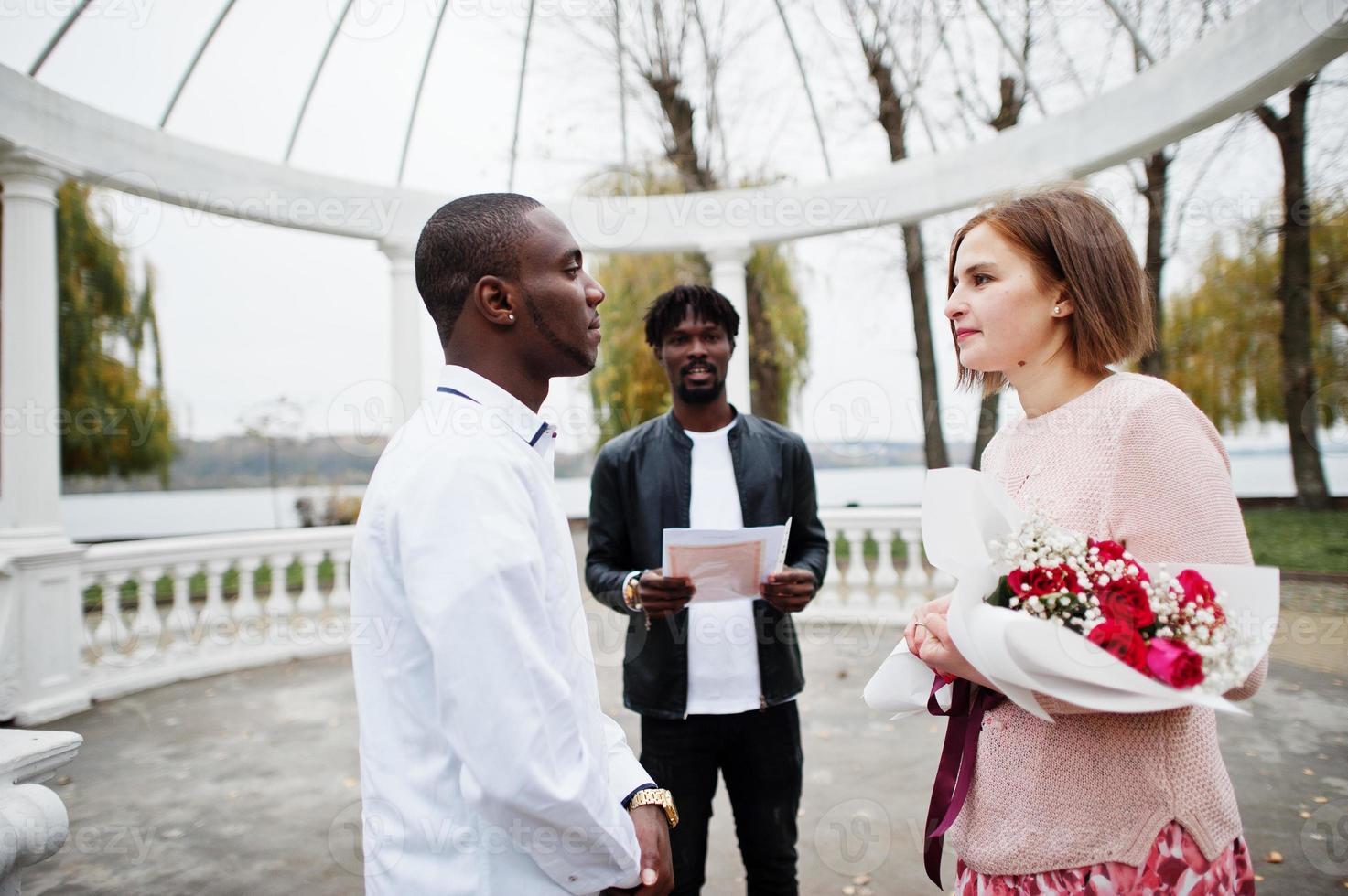 ceremonia de compromiso de boda con el pastor. feliz pareja multiétnica en la historia de amor. relaciones de hombre africano y mujer europea blanca. foto