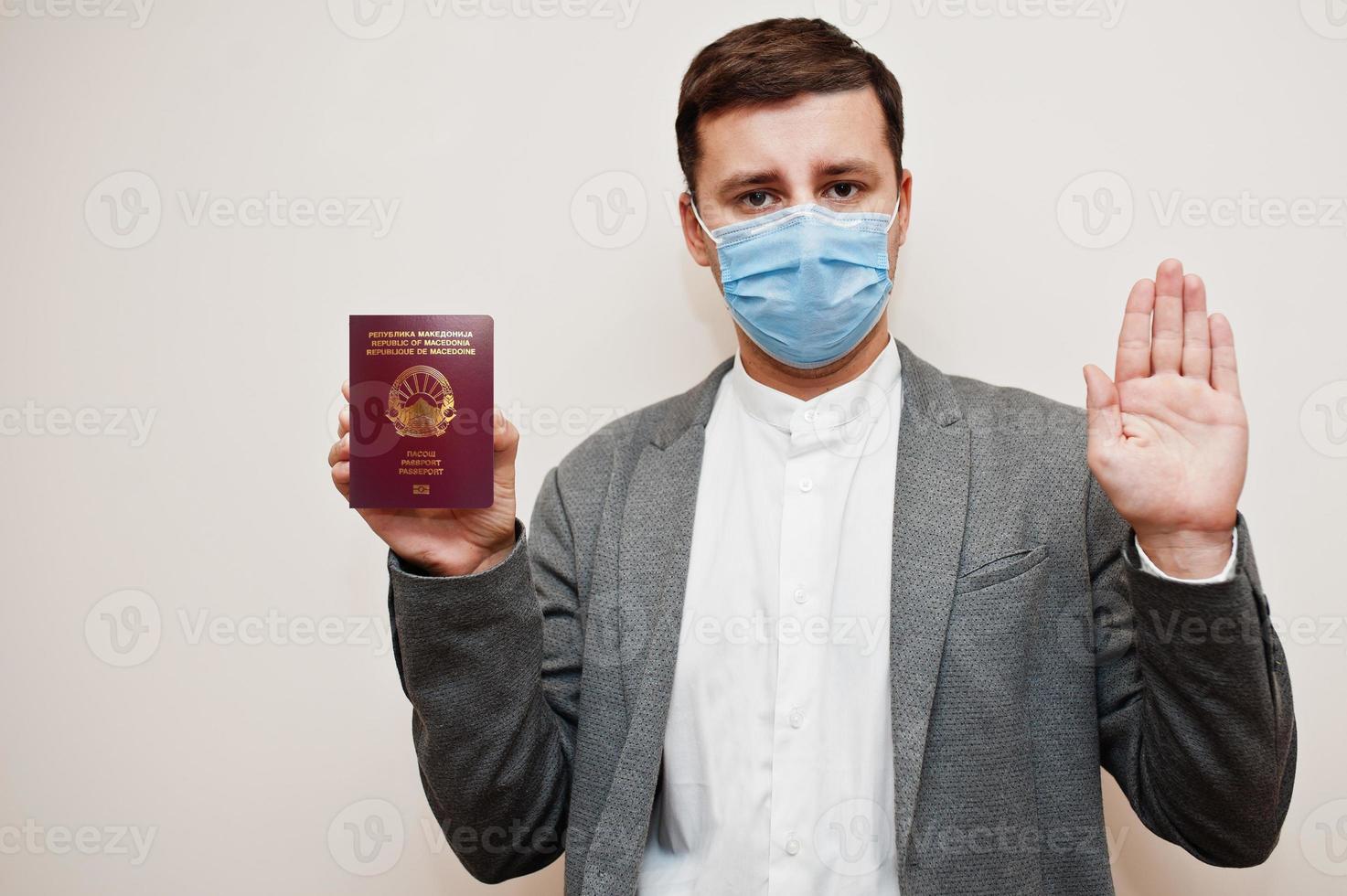 European man in formal wear and face mask, show North Macedonia passport with stop sign hand. Coronavirus lockdown in Europe country concept. photo