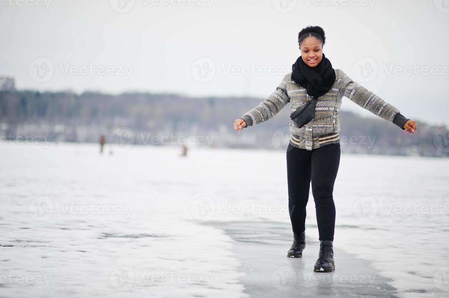 African woman wear in black scarf pose in frozen ice lake, winter day at Europe. photo