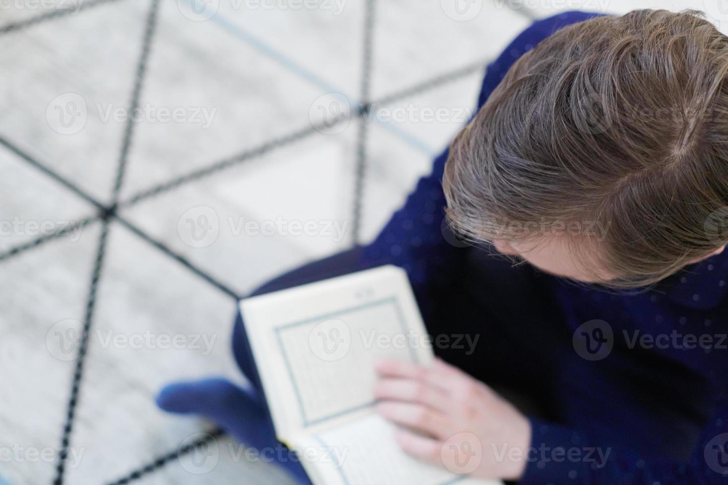 young muslim man reading Quran at home photo