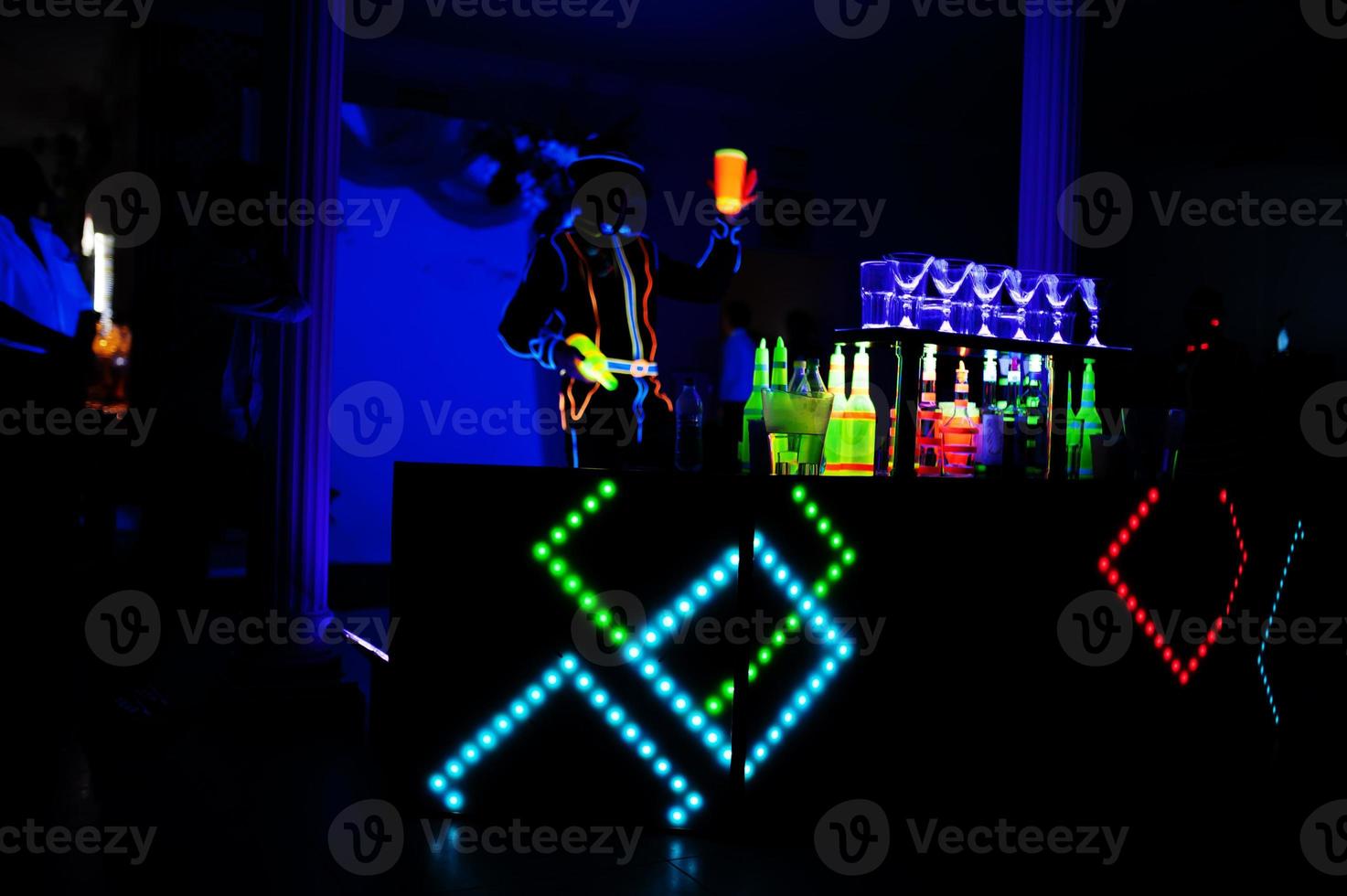 Professional barman and led light show. Silhouette of modern bartender shaking drink at night cocktail bar. photo