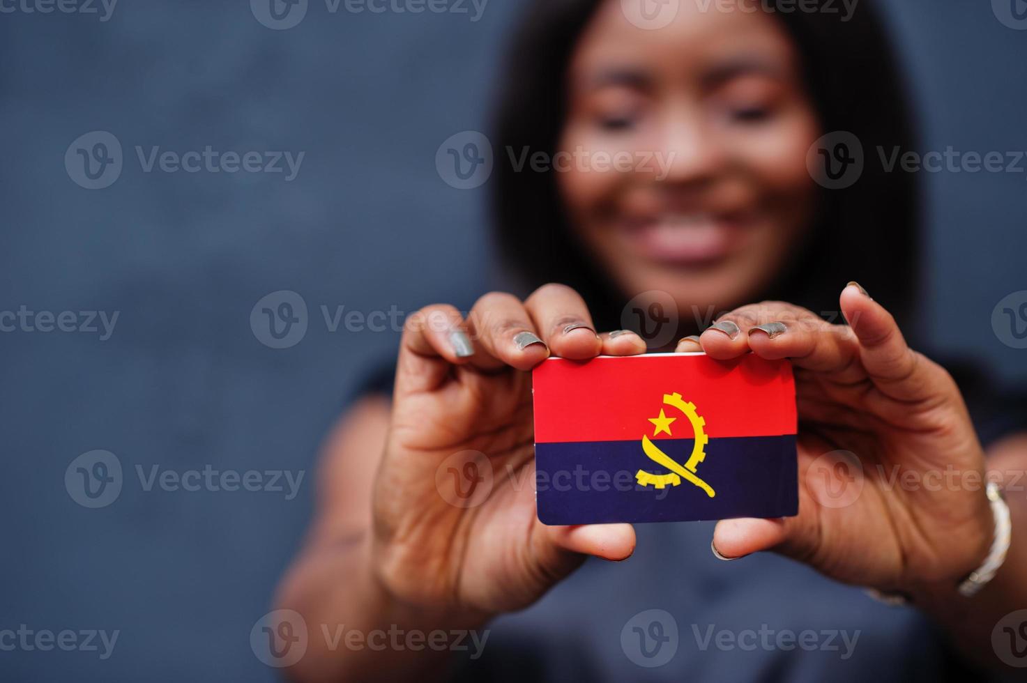 African woman hold small Angola flag in hands. photo