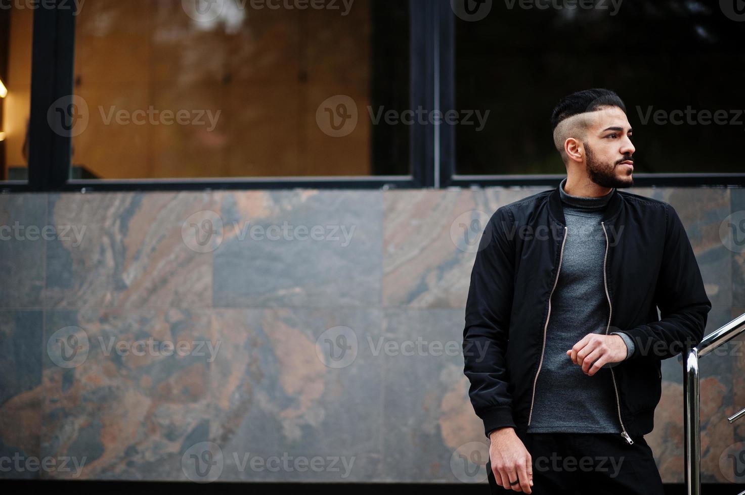 retrato de un elegante hombre de barba árabe con cuello alto gris y jaket negro. chico modelo árabe. foto