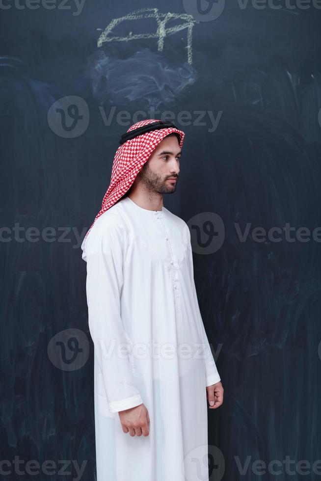 portrait of arabian man in front of black chalkboard photo