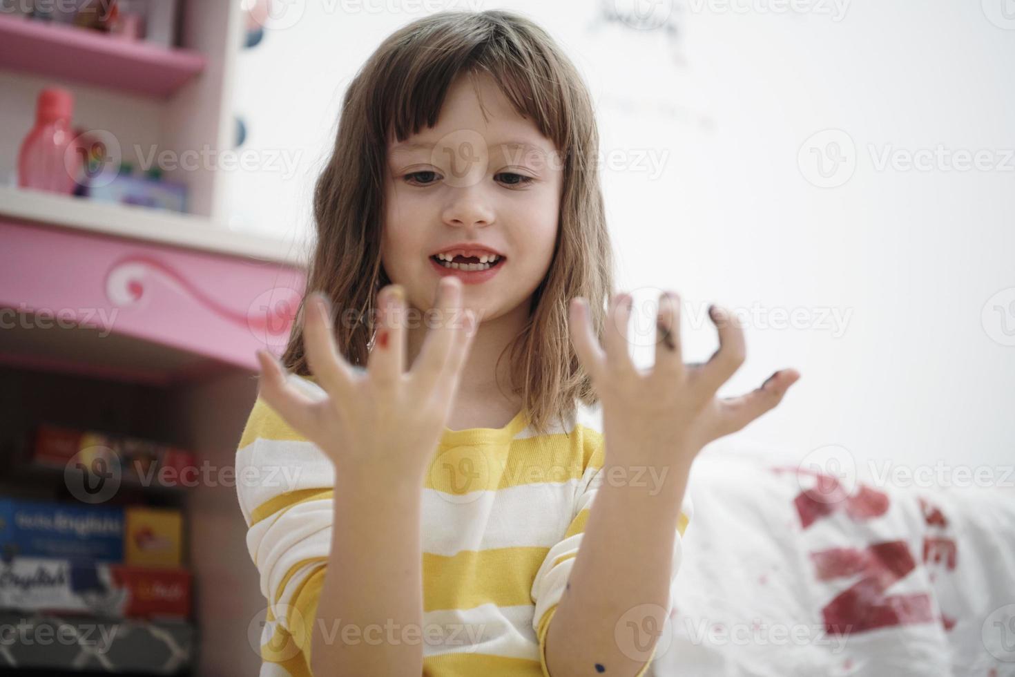 linda niña en casa pintando con las manos foto