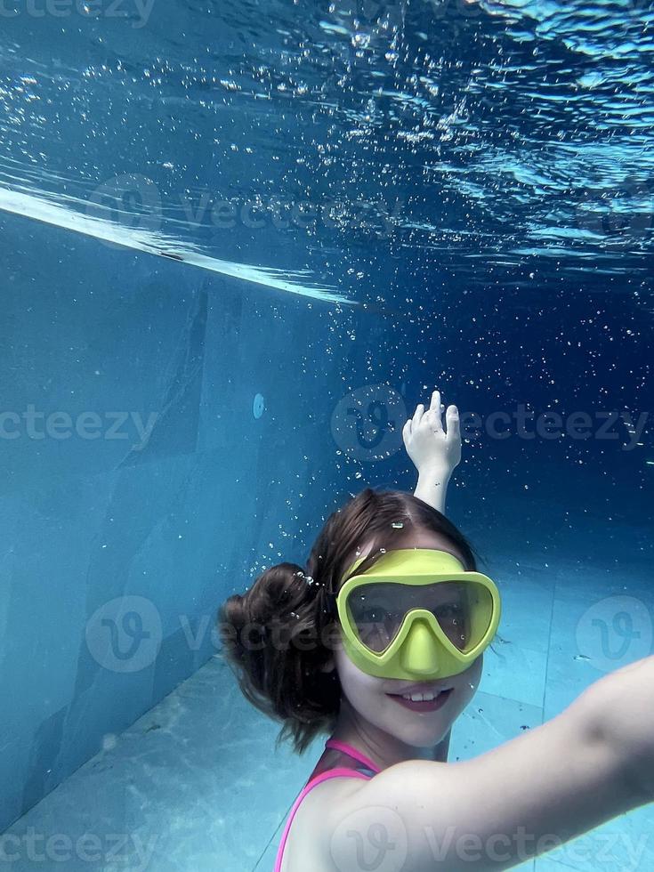 Smiling child in goggles swim, dive in the pool with fun - jump deep down underwater. Healthy lifestyle, people water sport activity on summers. photo