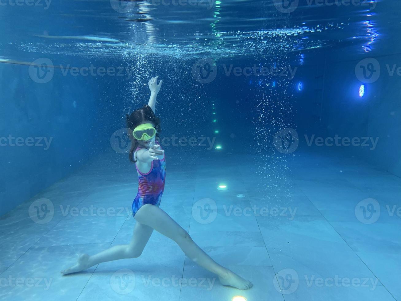 un niño sonriente con gafas nada, se sumerge en la piscina con diversión, salta profundamente bajo el agua. estilo de vida saludable, actividad de deportes acuáticos en los veranos. foto