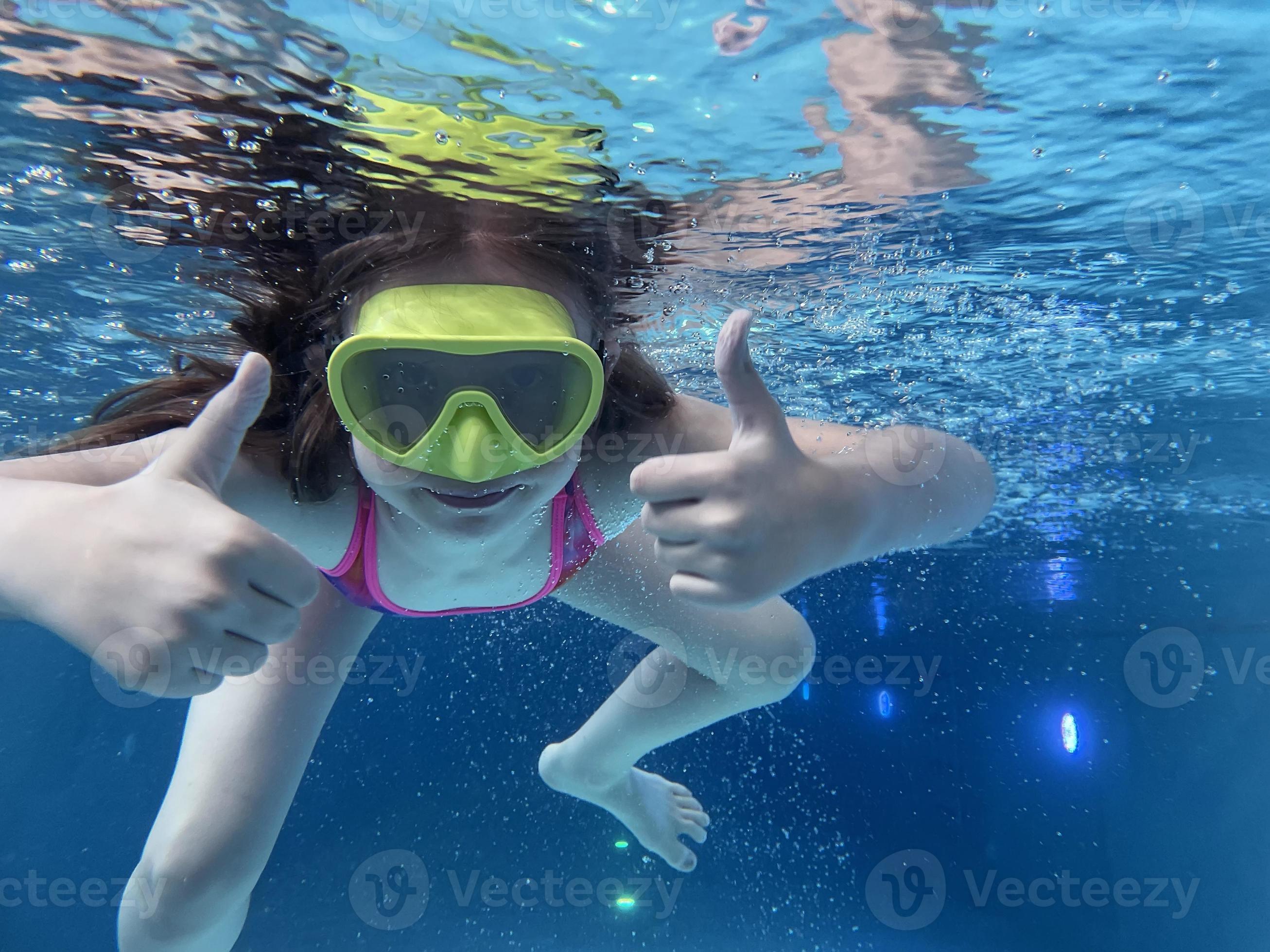 Smiling child in goggles swim, dive in the pool with fun jump deep