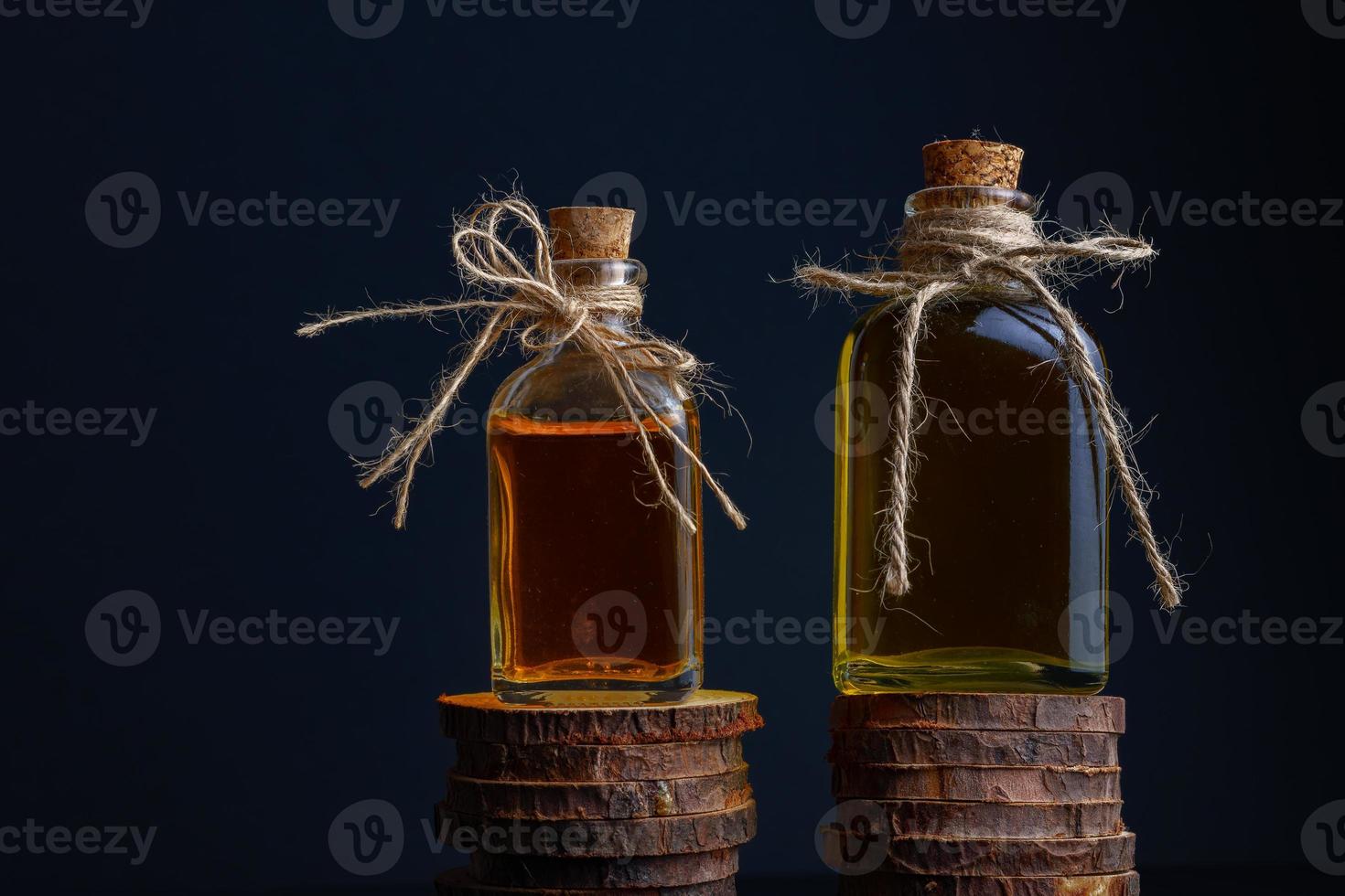 dos botellas de vidrio con tapón de corcho y hilo de rafia con aceite de romero y aceite de rosa foto