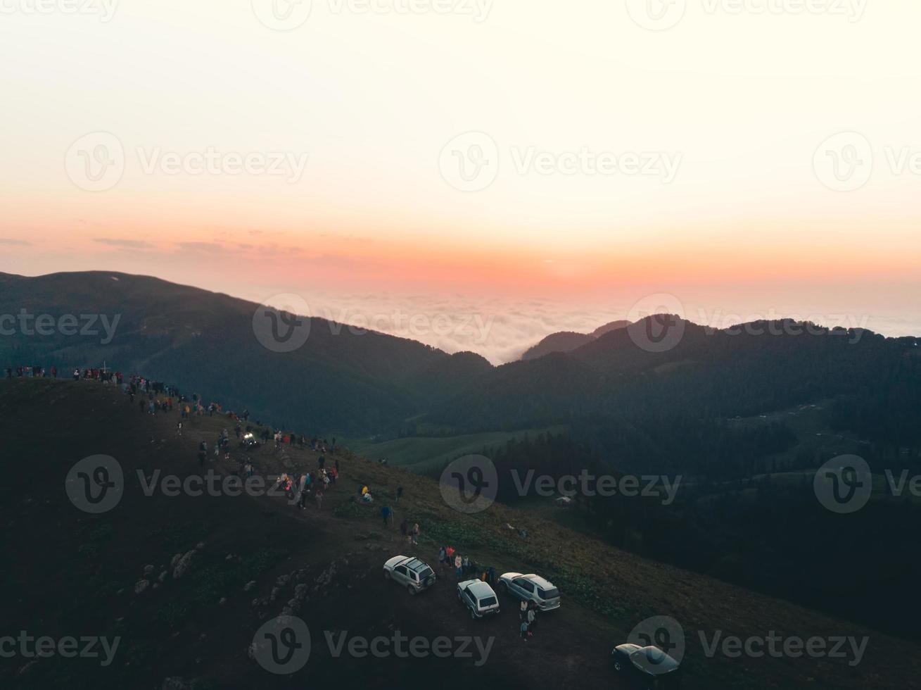 People on famous Bakhmaro sunset viewpoint watch sunset over clouds in Georgia photo