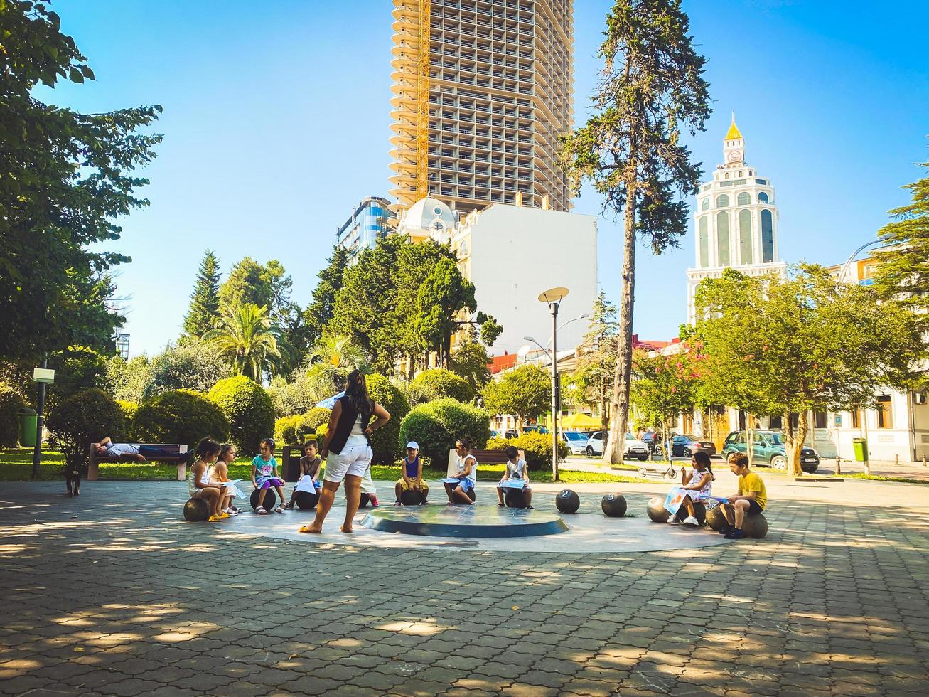 Batumi, Georgia, 2022 - teacher stand in park with kids study on school class activity outdoors in public park. Education and study childhood in big cities concept photo