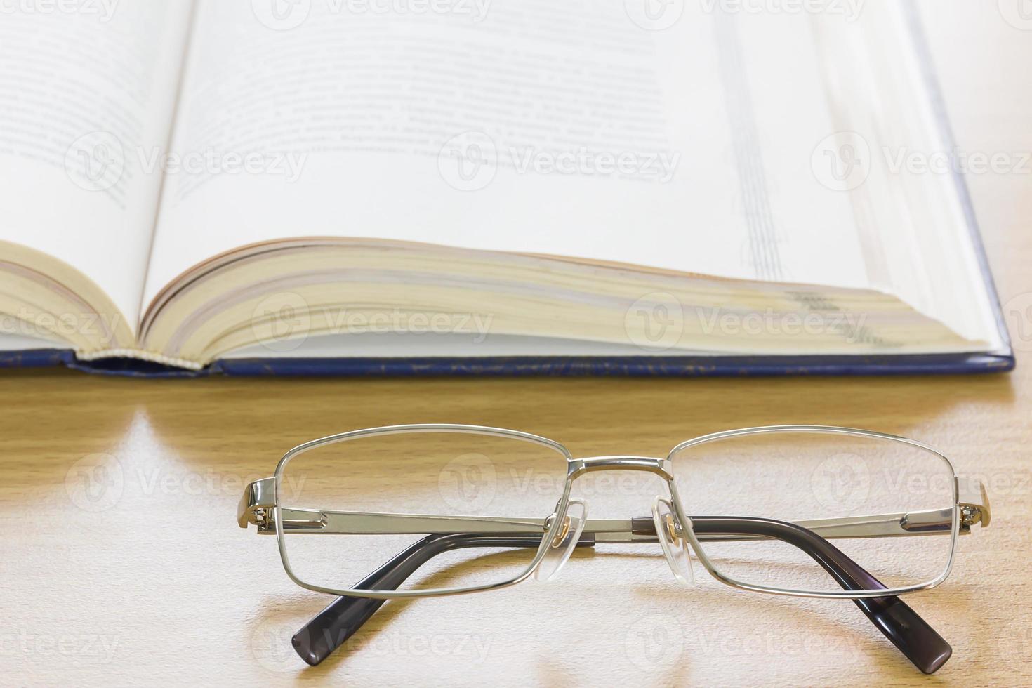 Close up glasses and a book on the desk photo