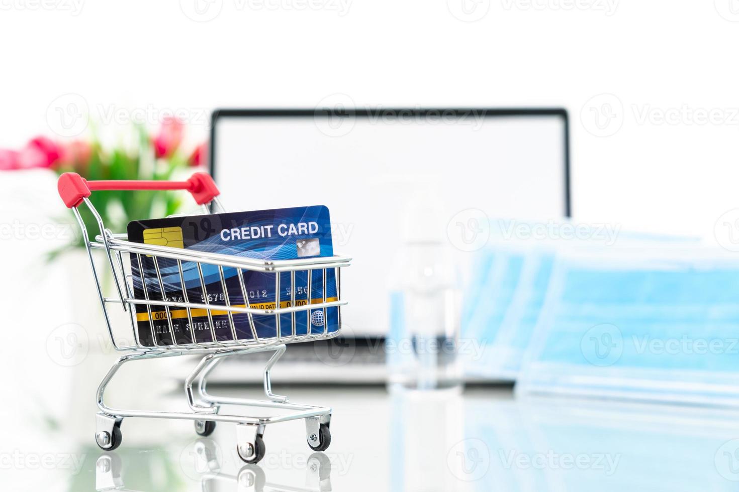 Credit card in shopping cart front of laptop screen with surgical mask photo