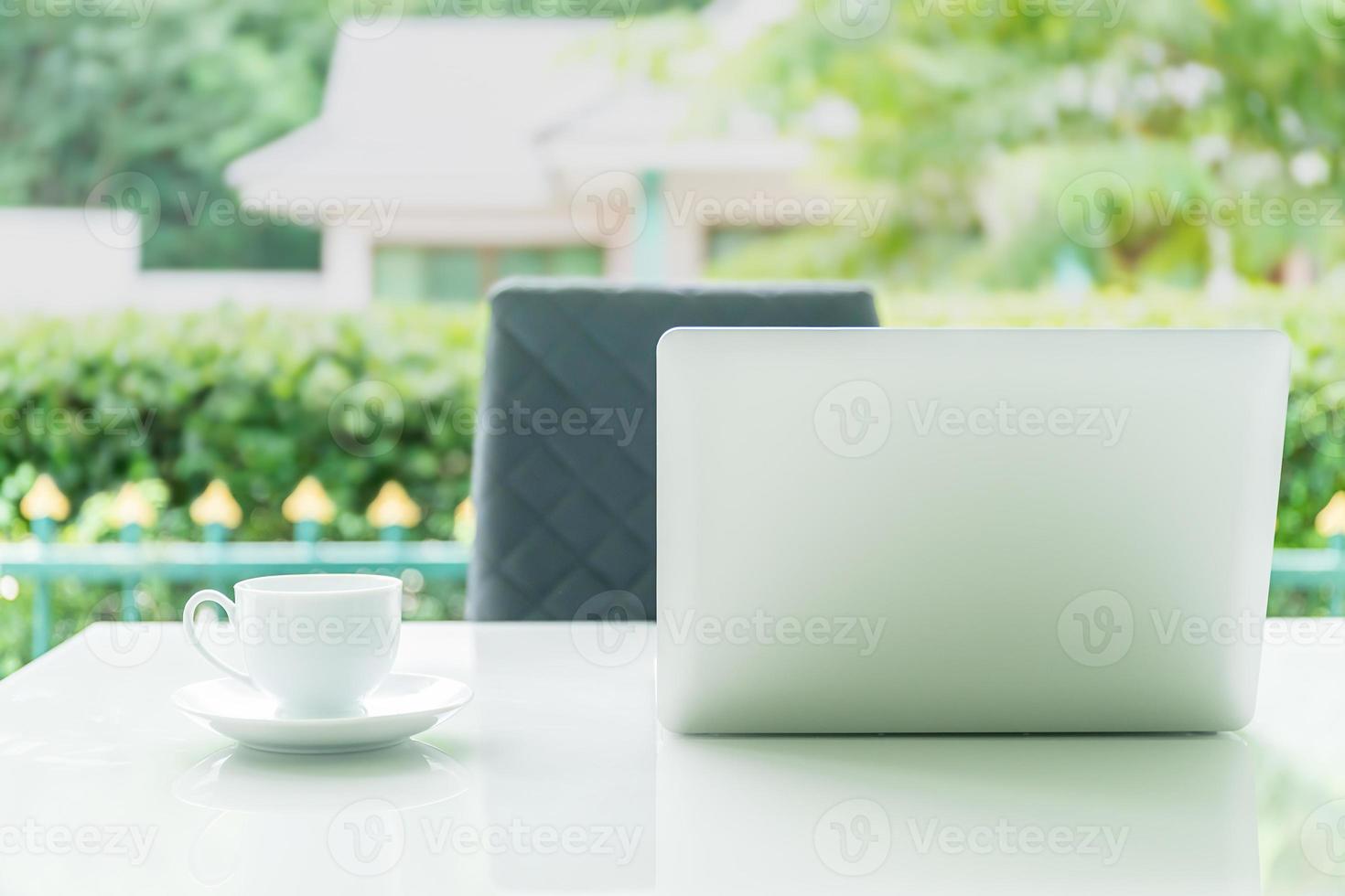Laptop computer and cup of coffee on the table in morning photo