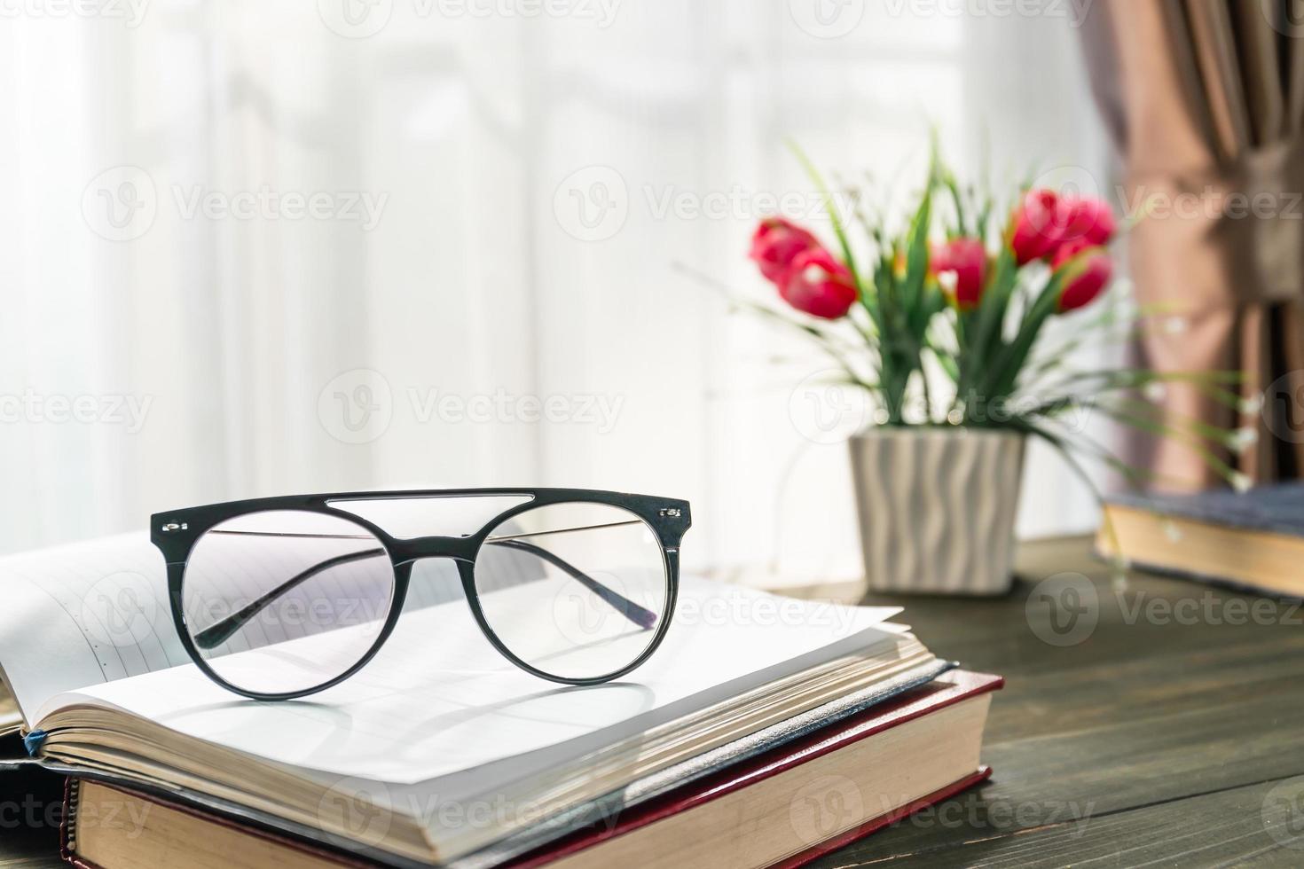 Reading glasses put on open book beside the window photo