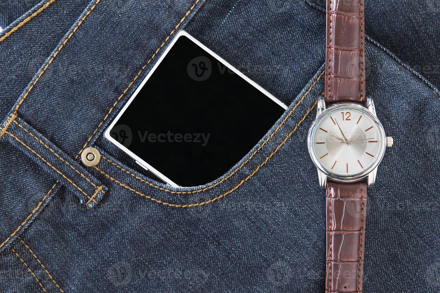 Wrist watch and smartphone on jeans photo